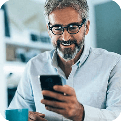 Photo : Un homme dans un café regarde son téléphone portable et sourit