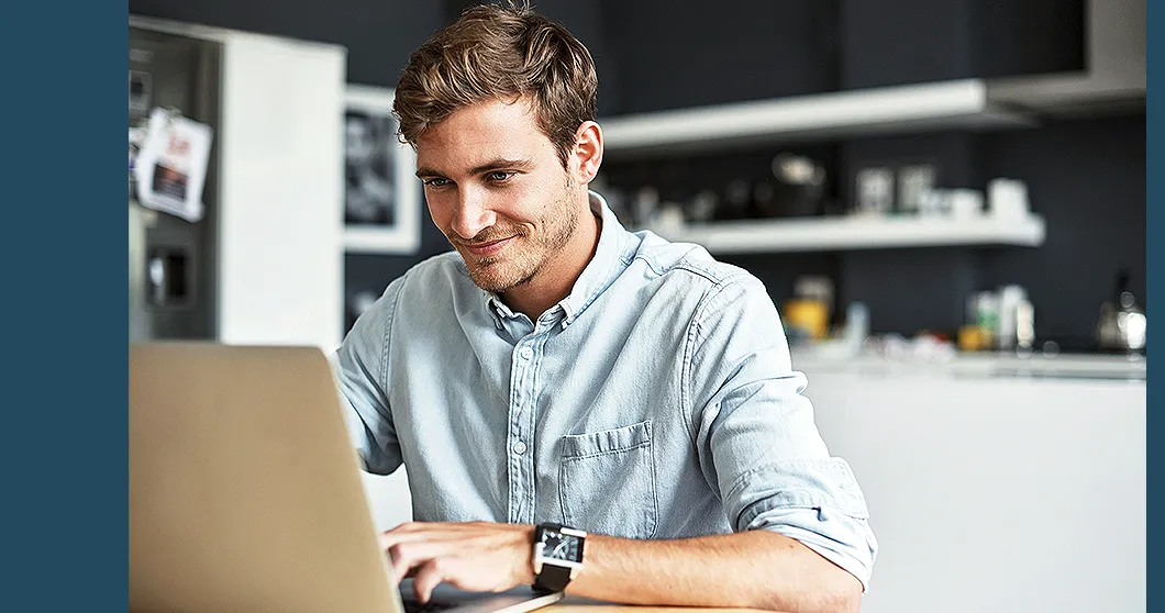 Un homme souriant devant un ordinateur portable